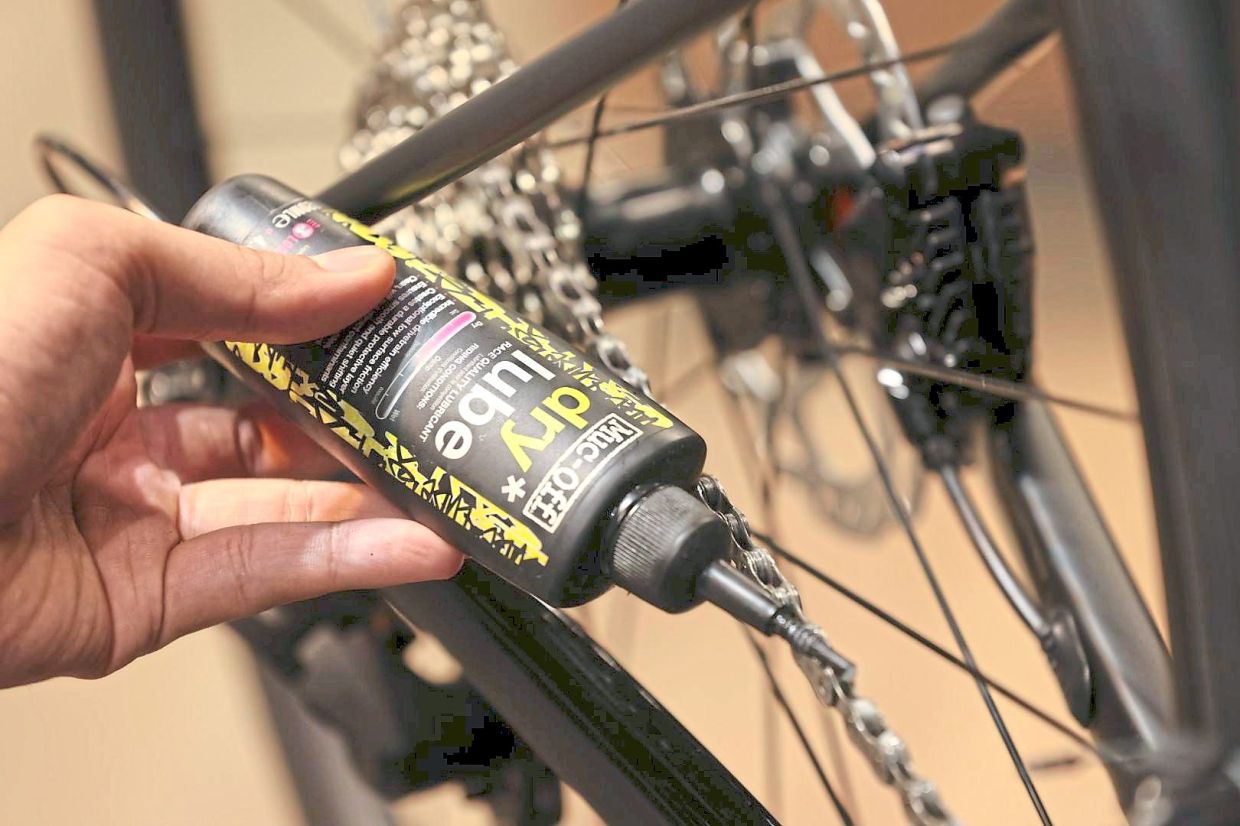 Applying dry lubricant to the chain after a clean-up.