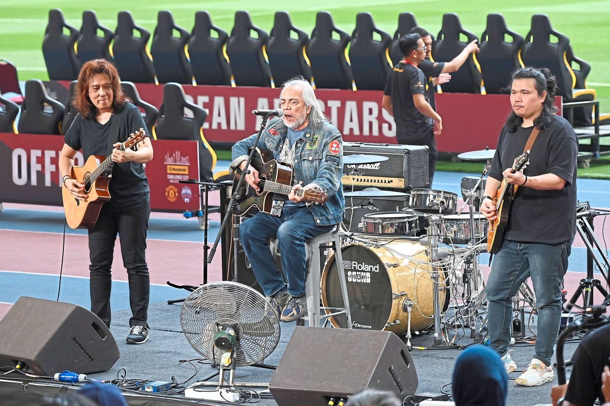 Datuk Ramli Sarip (centre) performing for spectators before the start of the match.