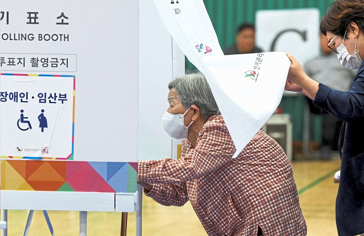 An elderly woman entering a booth at a polling station. — Reuters/AP