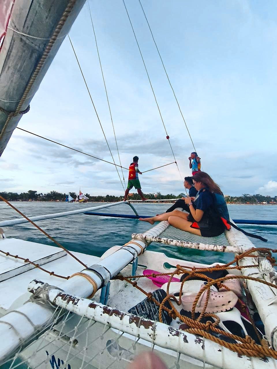Local boatmen walking around a paraw on small poles, while tourists sit cautiously on the net. — YASMIN ZULRAEZ 