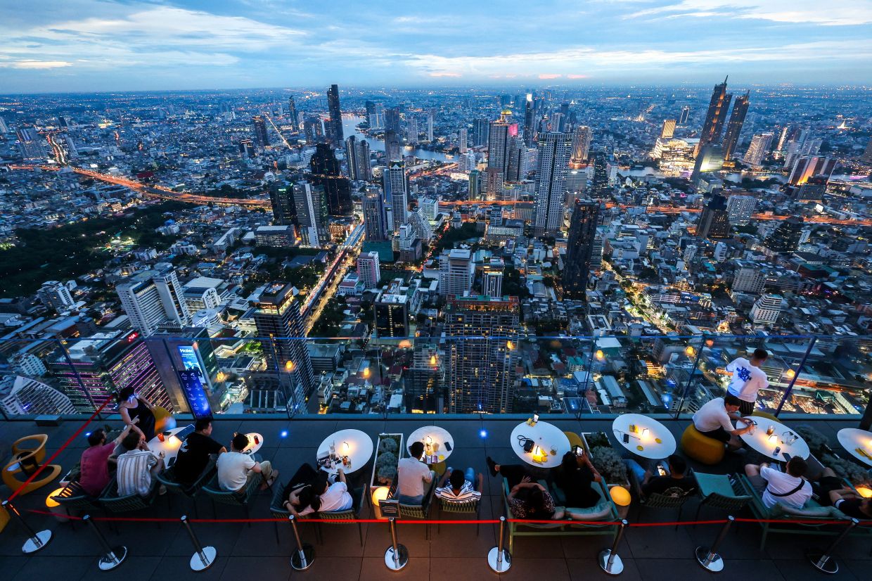 Tourists enjoying a view at the Mahanakhon Skywalk rooftop in Bangkok, Thailand. -- Photo: REUTERS/Athit Perawongmetha