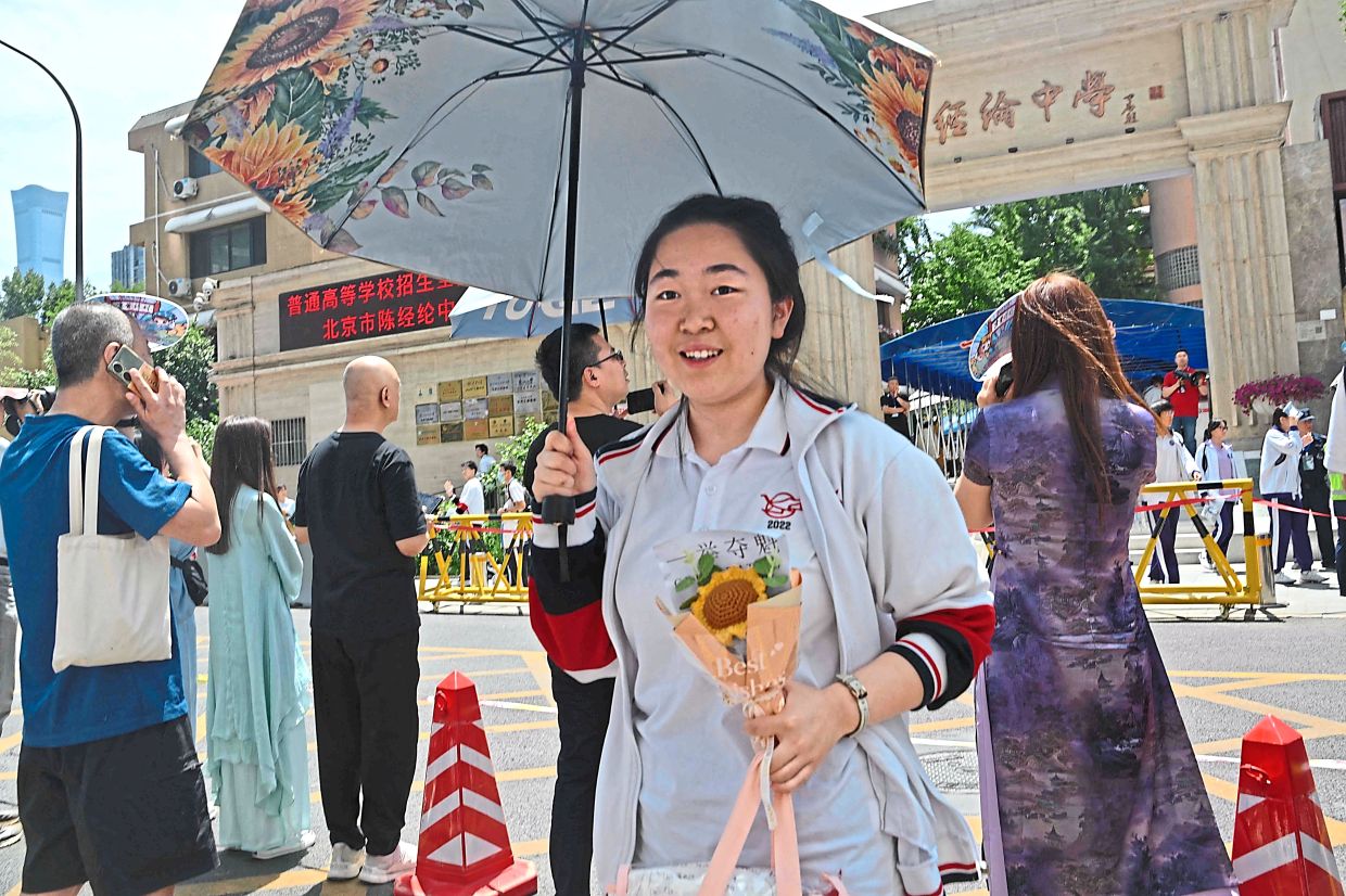 A student holding flowers after the first day of the exam, outside a school in Beijing. — AFP