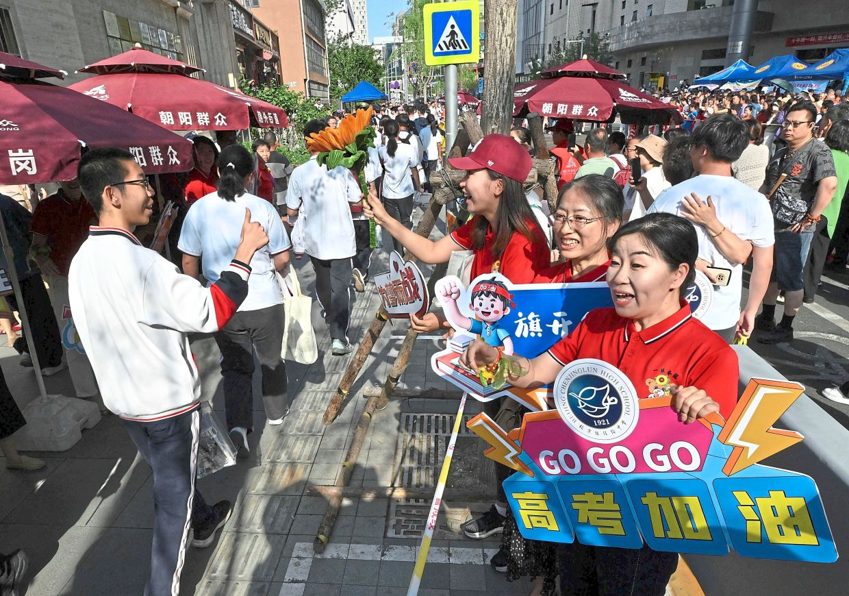 All the best: School staff members welcoming students as they arrive for the exam in Beijing. — AFP