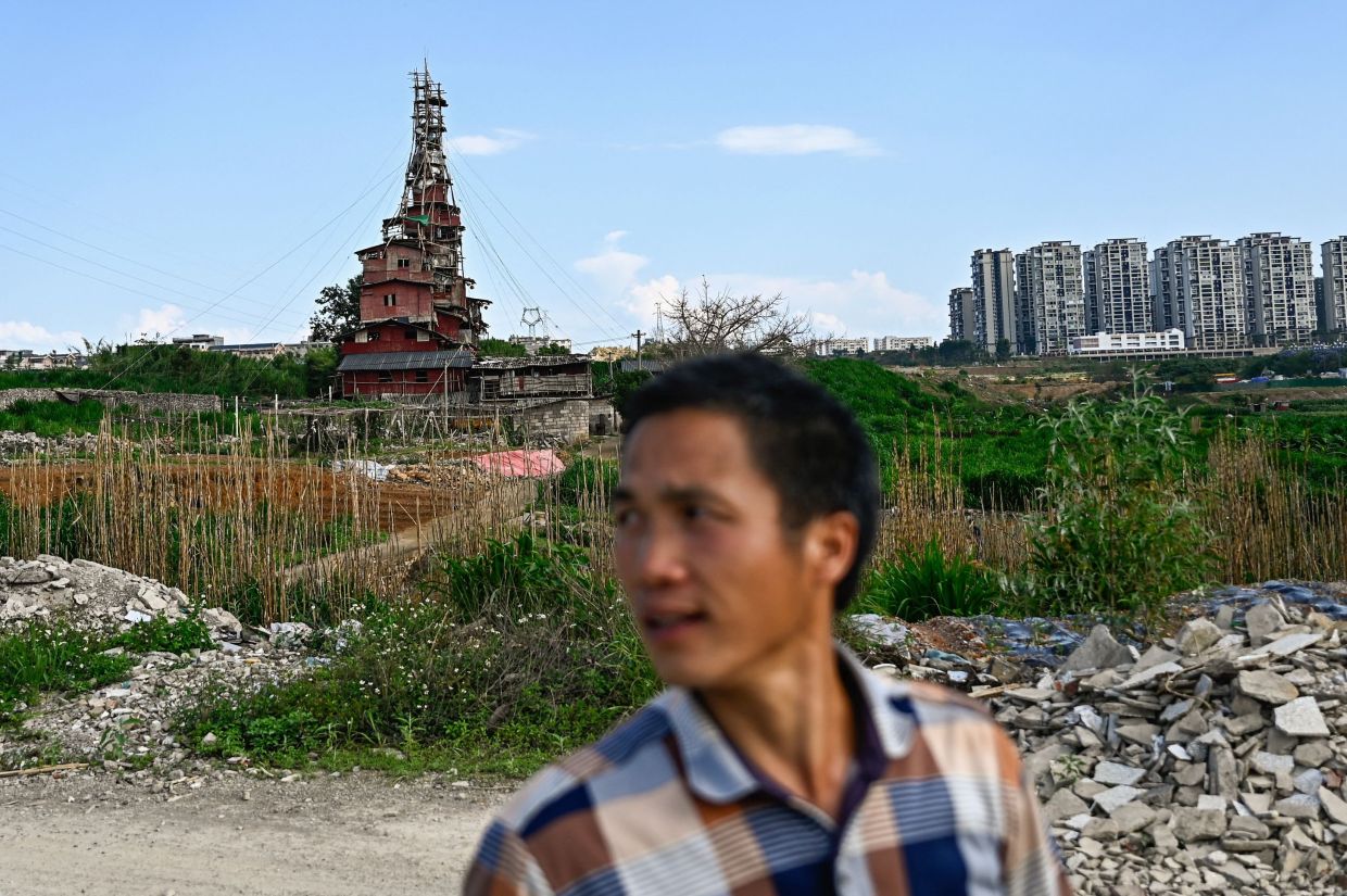Chen Tianming standing near his house labelled China's strangest -- nail house -- households that refuse to move in the face of development plans -- in Xingyi, in southwest Guizhou province. Chen, 42, has spent seven years and over 100,000 yuan ($13,900) defying authorities' demolition notices to turn his family's humble stone bungalow on the outskirts of Xingyi city into a bewildering 10-storey pyramid-shaped home that has drawn comparisons on Chinese social media to the fantastical creations of Japanese animator Hayao Miyazaki. -- Photo by Pedro PARDO / AFP
