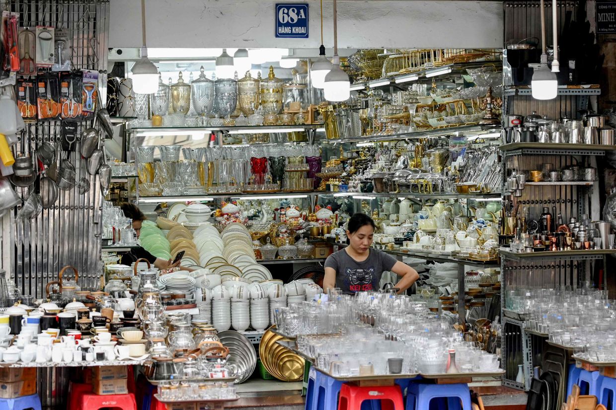 A saleswoman uses her phone as she waits for customers at a home appliance store in Hanoi on June 6, 2025. Vietnam's exports rose sharply last month, official figures showed June 6, as the communist country tries to negotiate relief from swingeing tariffs threatened by US President Donald Trump. -- Photo by Nhac NGUYEN / AFP