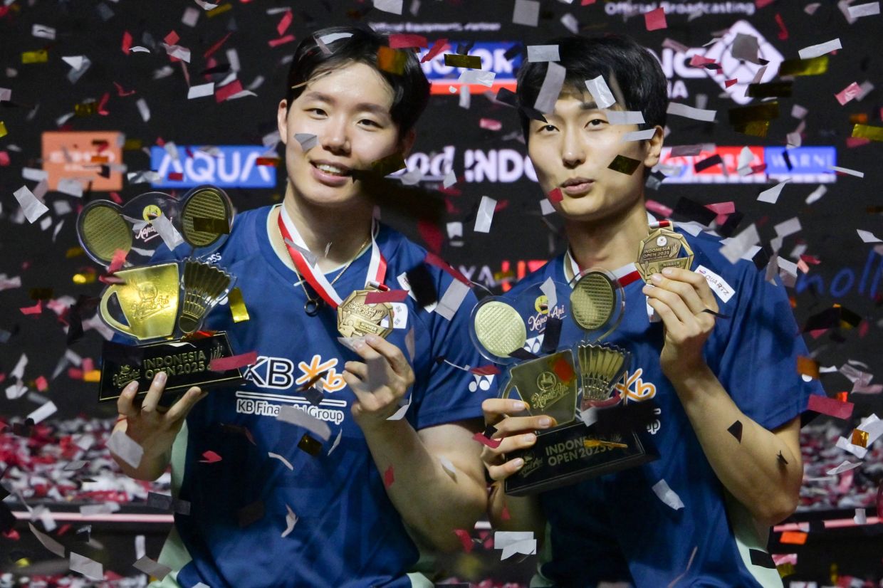 South Korea's Kim Won-ho and Seo Seung-jae celebrate on the podium following their victory against Indonesia's Sabar Karyaman Gutama and Moh Reza Pahlevi Isfahani during their men's doubles final match at the Indonesia Open badminton tournament at Istora Senayan in Jakarta on Sunday, June 8, 2025. -- Photo by BAY ISMOYO / AFP