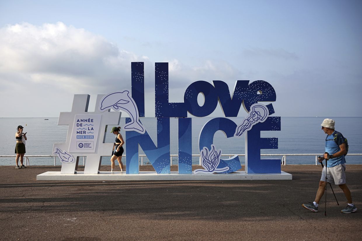 People walk on the sea promenade ahead of the UN Ocean Conference in Nice, French Riviera. -- AP Photo/Laurent Cipriani