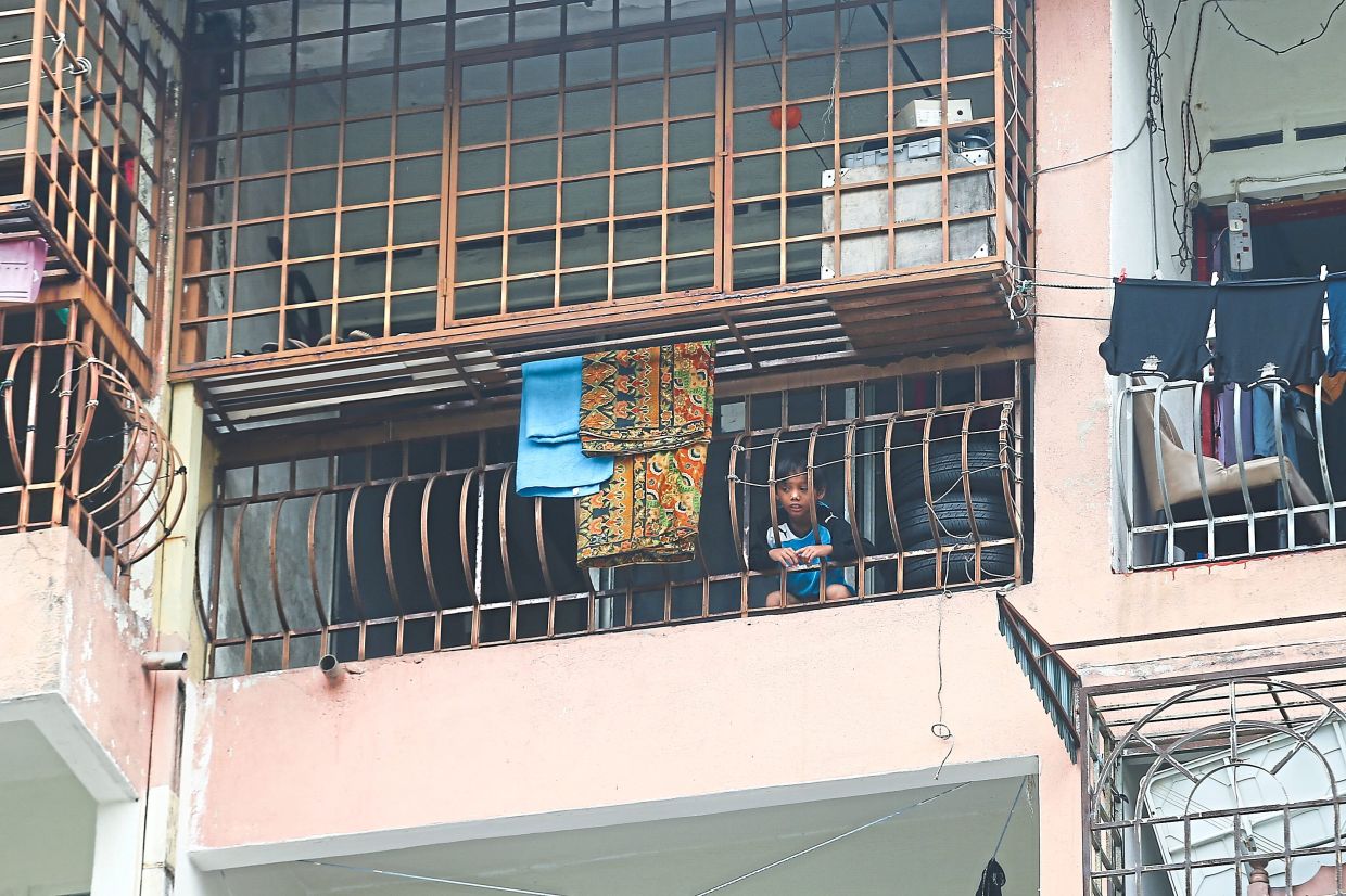 A child looking out the grilles of the balcony at his strata home in Shah Alam. — Filepic
