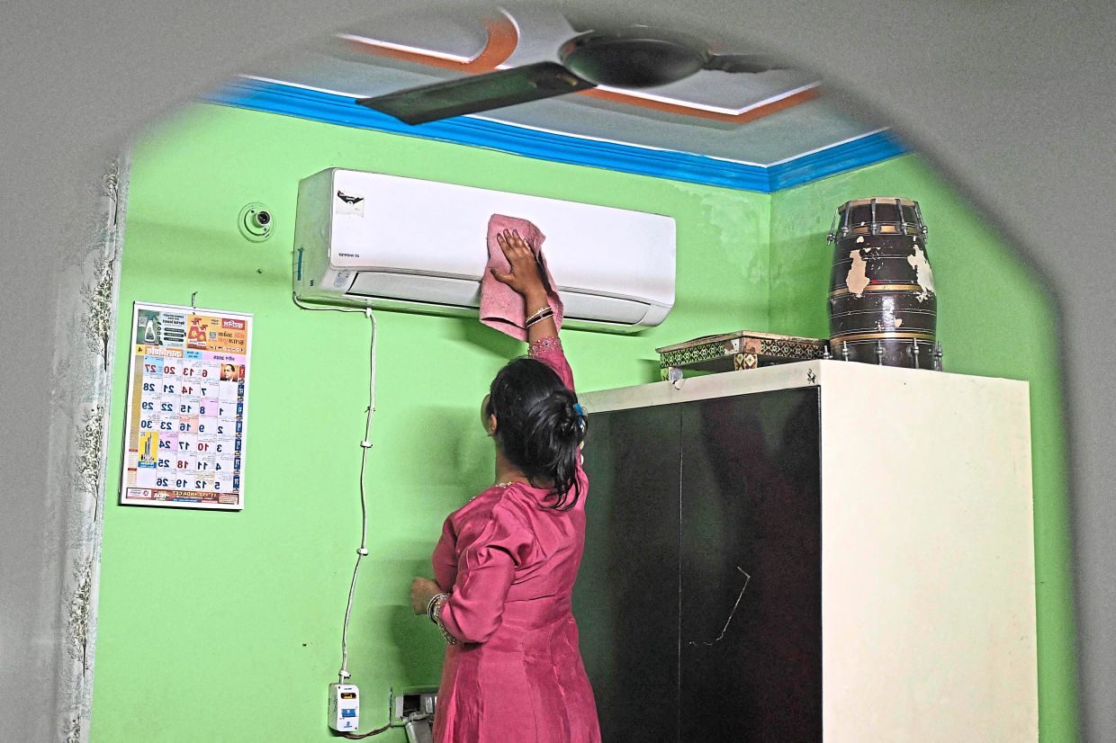 Verma cleaning an air conditioner installed inside her house in New Delhi. — AFP