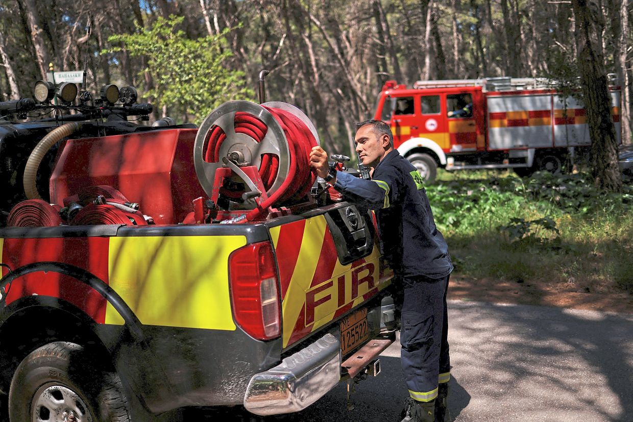Volunteer Forest Firefighters Rescue Team member Panagiotis Mastoris, 38, checking a hose during a patrol in Ekali, northern Athens. — Reuters