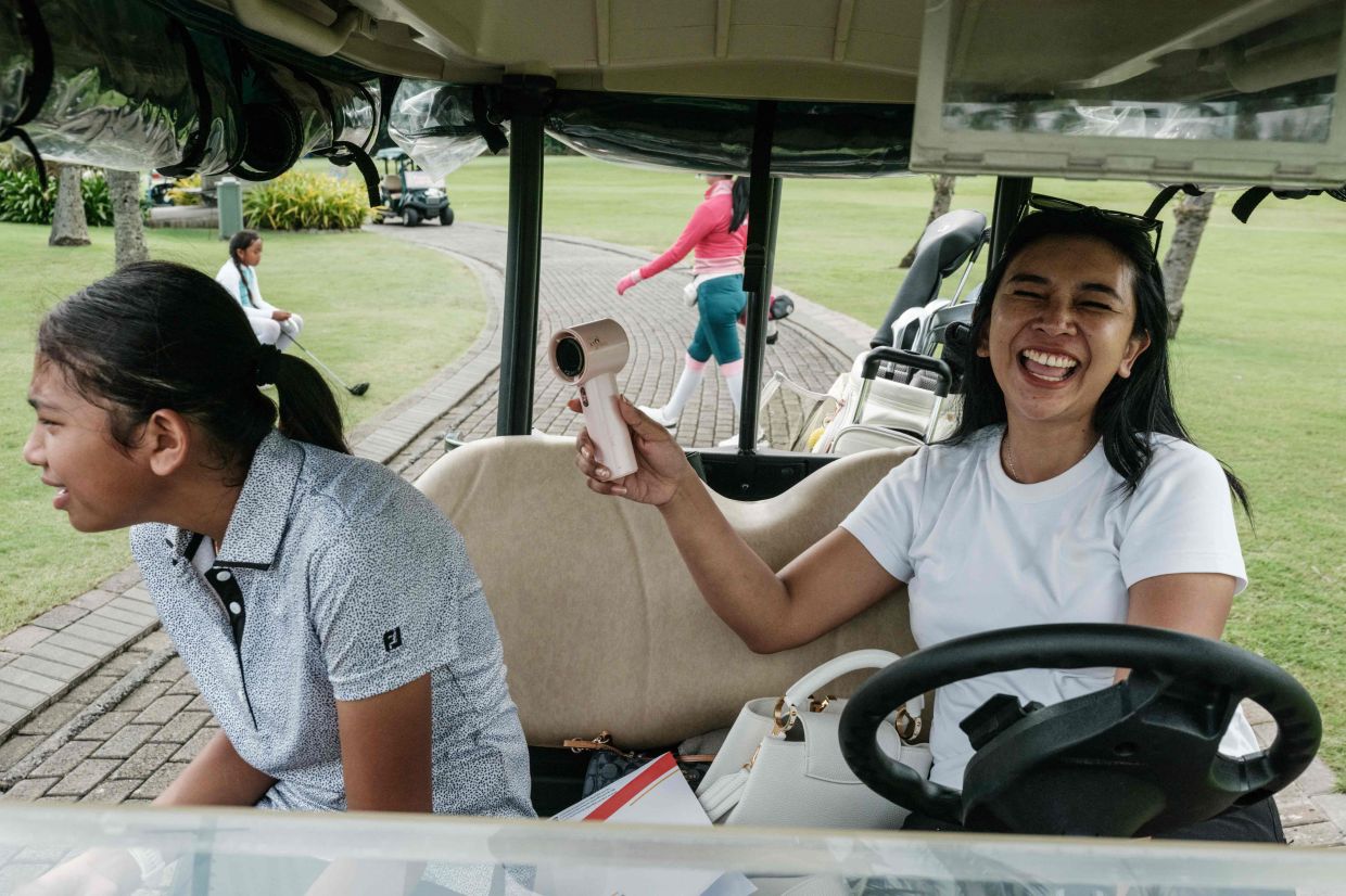 Indonesian golfer Queen Shine Gracella (left), 10, reacts with her mother during training ahead of the Mandiri Ciputra Golfpreneur Junior World Championship 2025, a two-day tournament with 141 players aged 10 to 18 from 21 countries, at the Damai Indah Golf PIK course in Jakarta on Monday, June 9, 2025. -- Photo by YASUYOSHI CHIBA / AFP