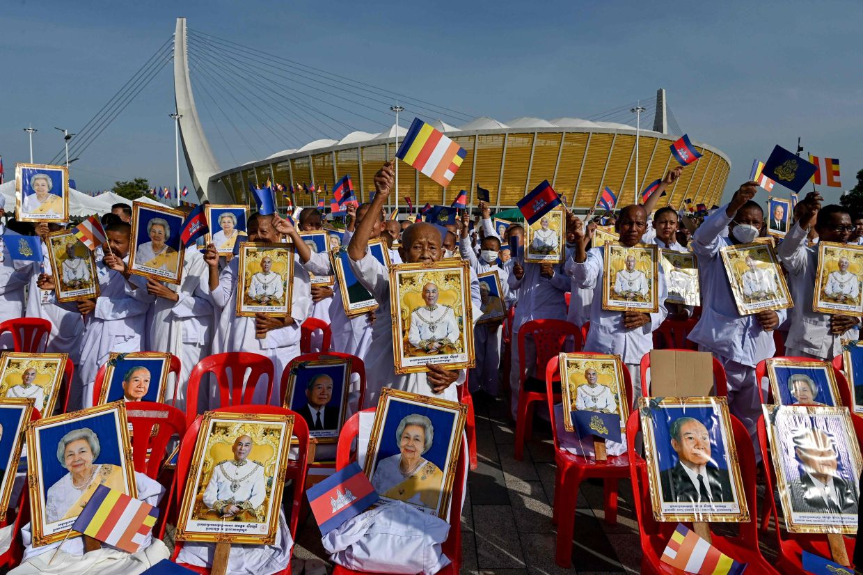 Nuns and attendees hold portraits of Cambodia's King Norodom Sihamoni, Queen Mother Norodom Monineath Sihanouk, and the late king Norodom Sihanouk at an event to mark Cambodia's Environment Day and the United Nations' World Environment Day at Morodok Techo National Stadium in Phnom Penh. -- Photo by TANG CHHIN Sothy / AFP