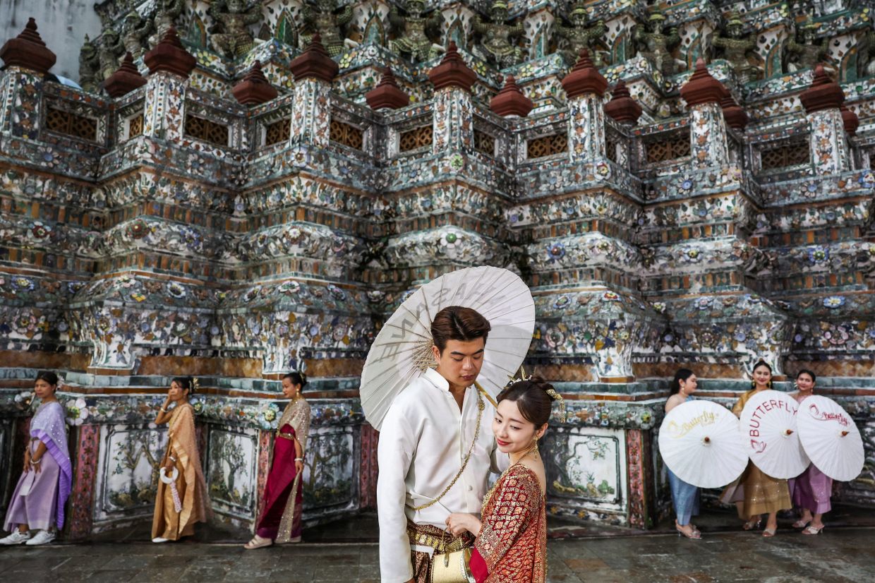 Tourists dressed in traditional Thai costumes pose for pictures as they visit Wat Arun or the Temple of Dawn, in Bangkok. -- Photo: REUTERS/Chalinee Thirasupa