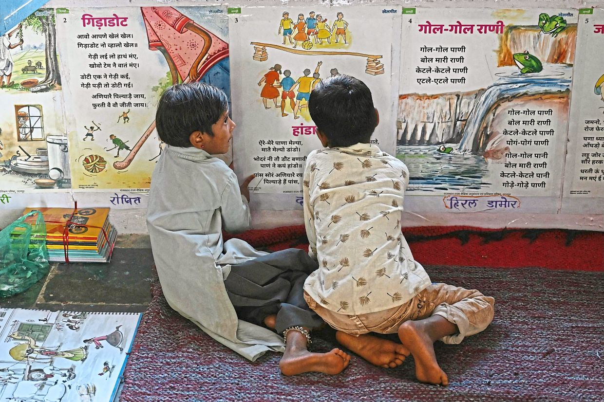Students read the study material pasted on the wall of their classroom. Photo: MONEY SHARMA/AFP