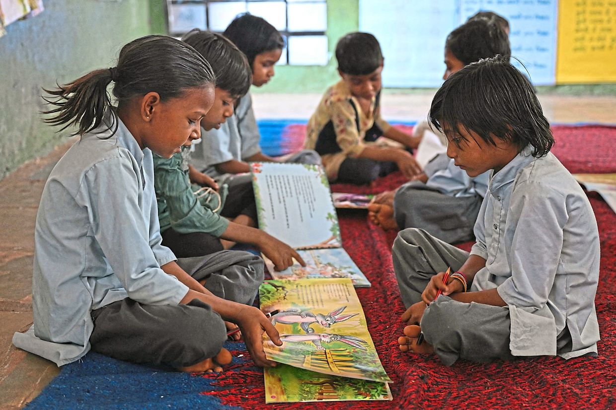 Young students read books in the classroom of a government primary school. Photo: MONEY SHARMA/AFP