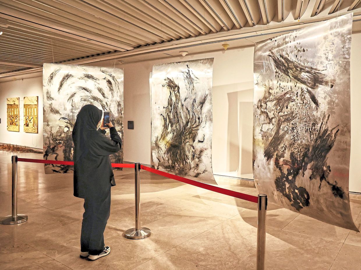 A visitor photographs Yuki Mun’s ‘Inner Portal, Outer World’, a new artwork created using ink on aluminium. Photo: The Star/Muhamad Shahril Rosli
