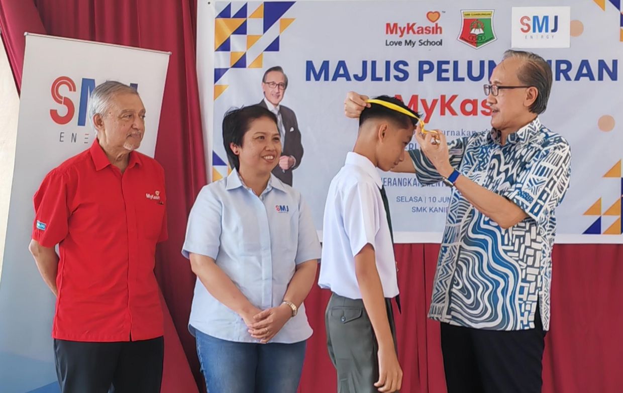Finance Minister and SMJ Energy Sdn Bhd chairman Datuk Seri Masidi Manjun presenting the smart card to one of the SMK Kanibongan recipients, while SMJE chief executive officer Dr Dionysia Kibat (second right) and MyKasih Foundation deputy deputy chairman Jeffrey Perera (right) look on.