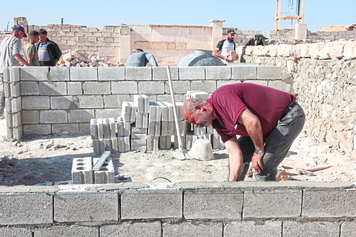 Mustafa Marouch rebuilds a wall in his destroyed house in Aleppo, Syria, April 19, 2025. REUTERS/Mahmoud Hassano