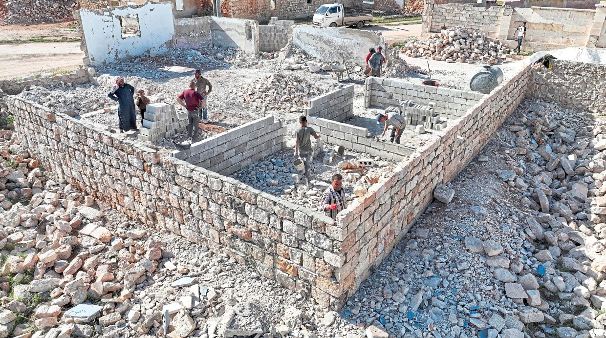 Mustafa rebuilding a wall in his destroyed house and (below) a drone view of people rebuilding a house in Aleppo. — Reuters