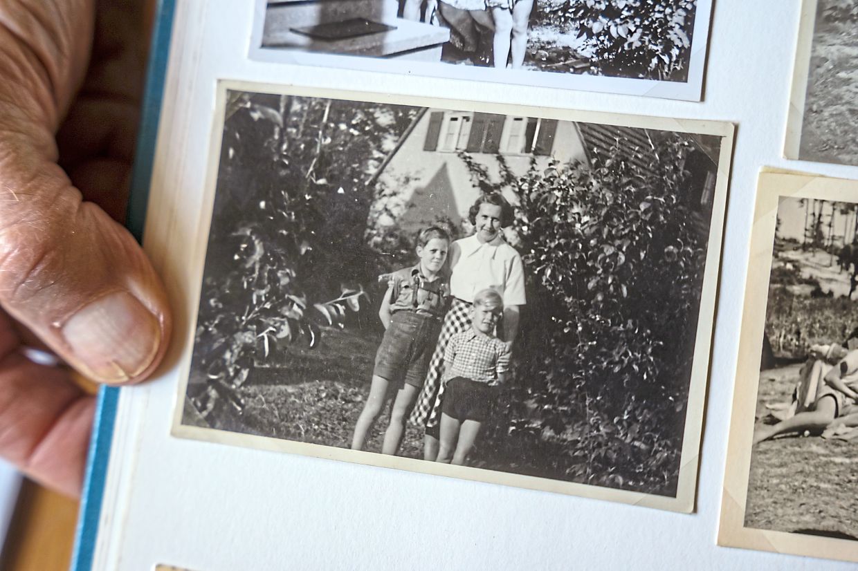 Joachim, with his mother and older brother outside their house, has lived in Waldsiedlung Krumme Lanke since 1946; and (right) Joachim standing outside his house. — Patrick Junker/The New York Times