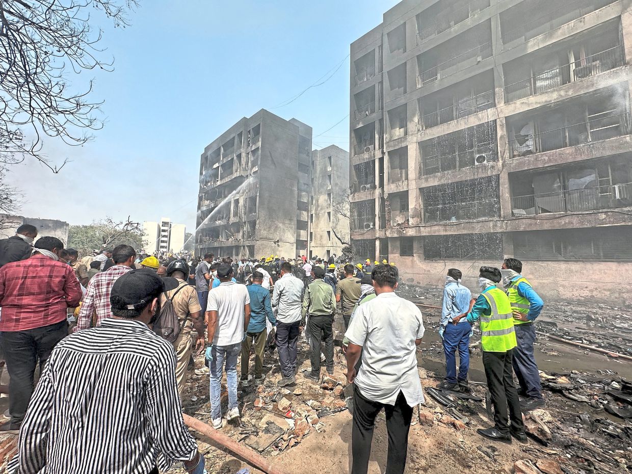 Tragic accident: People gathering near the site where an Air India plane crashed in Ahmedabad as firefighters (right) get to work. — Reuters/AFP