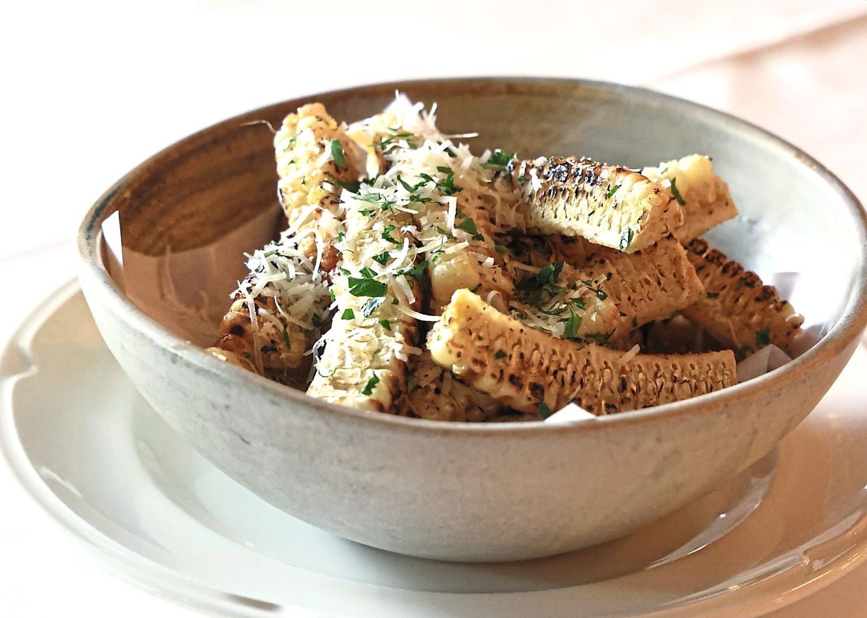 Brian says that his children have developed very good palates and are adventurous eaters. These corn ribs at Bistrot David, for instance, are Hayley's favourite dish. — ART CHEN/The Star