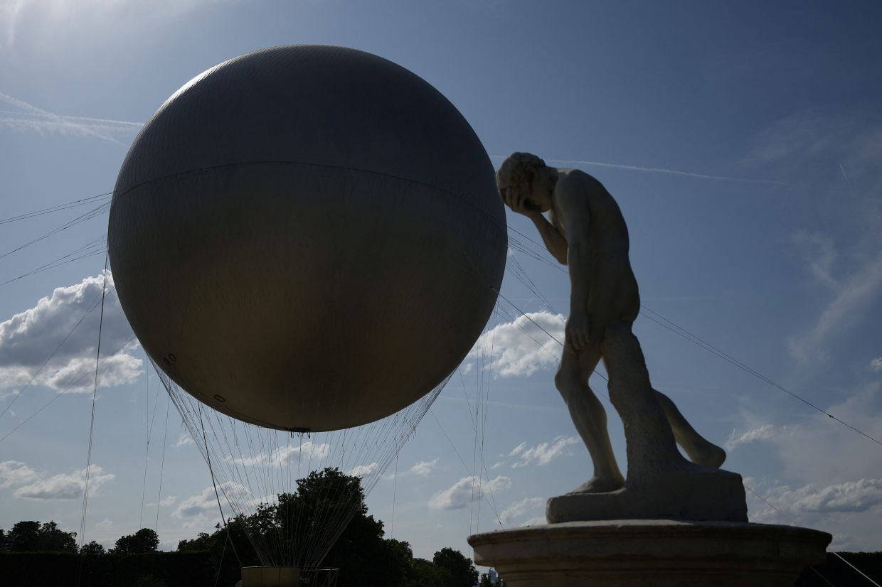 A view of a sculpture of the biblical Cain by Henri Vidal next to the Olympic cauldron and its balloon on the day of a visit by French President Emmanuel Macron, at the Tuileries Garden in Paris, France, 12 June 2025. YOAN VALAT/Pool via REUTERS