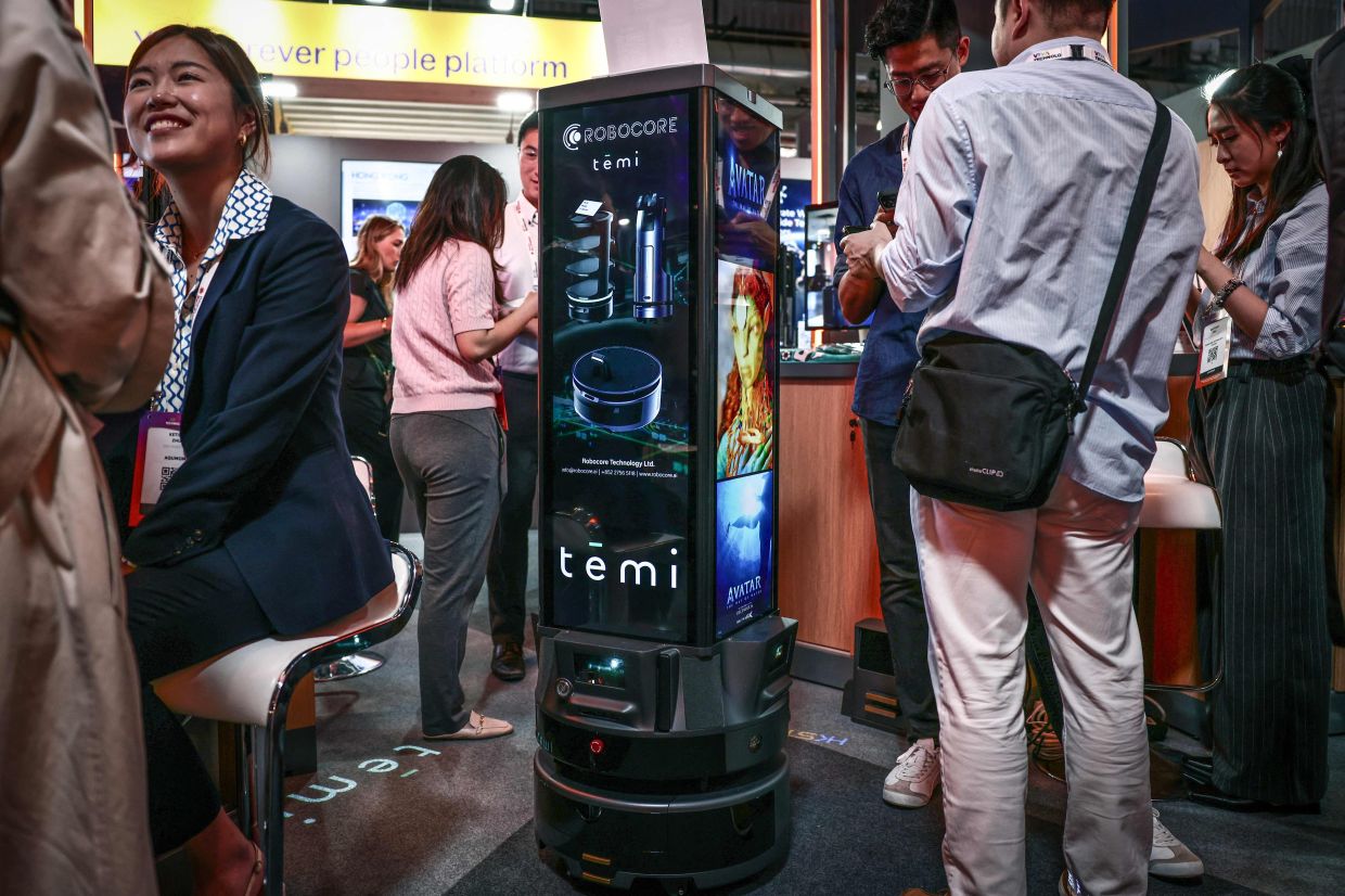 Visitors stand next to a Robocore mobile advertising robot 'Fourcast' at the 9th edition of the VivaTech technology startups and innovation fair in Paris on June 11, 2025. — AFP