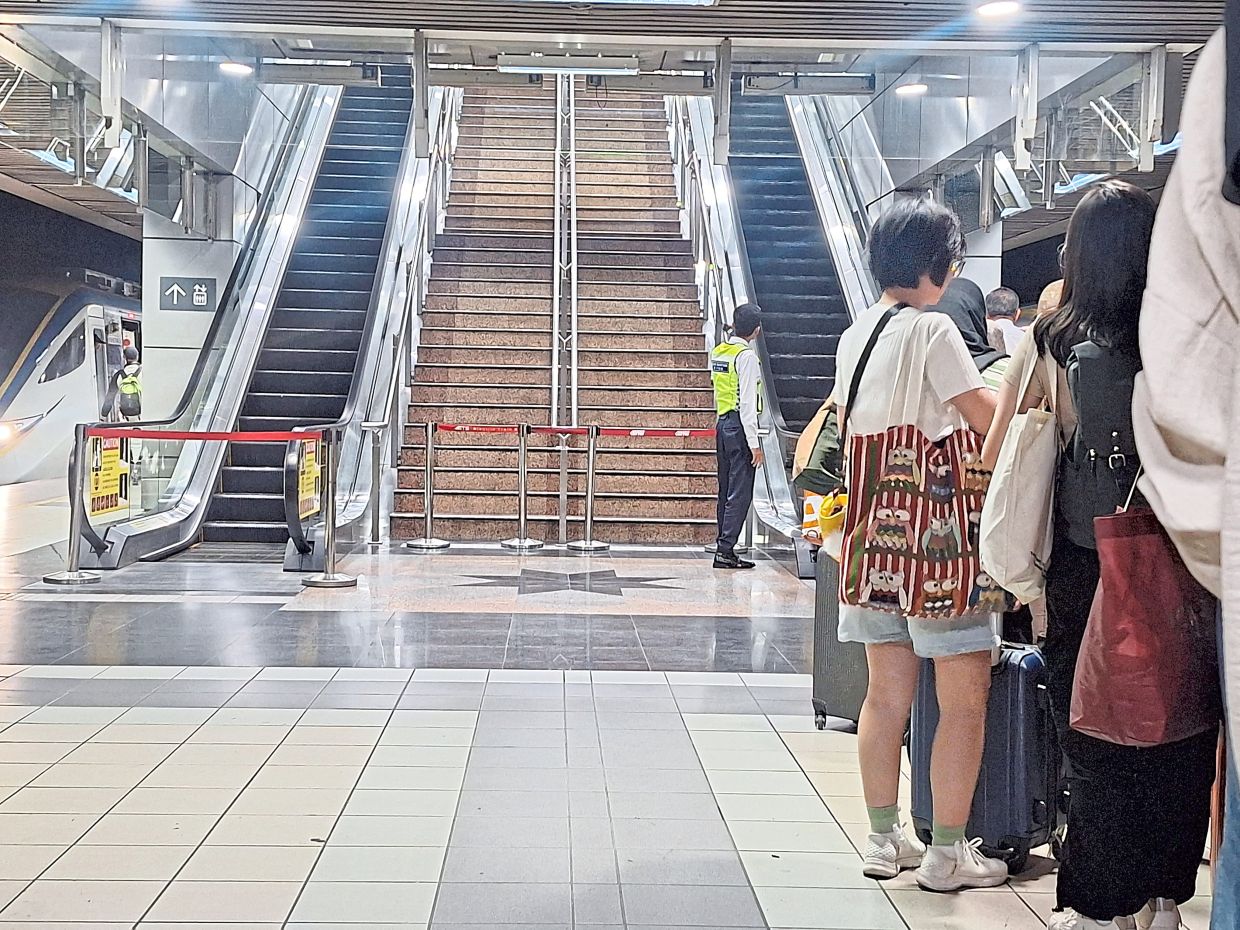 Tired passengers from the delayed northbound ETS train at KL Sentral station waiting at the escalator as the stairs have been sealed off.