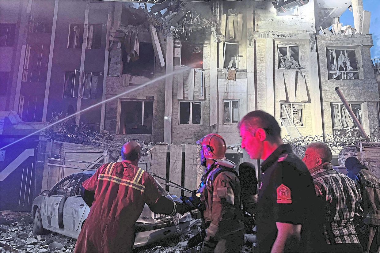 First-responders gathering outside a building that was hit by an Israeli strike in Tehran. — AFP