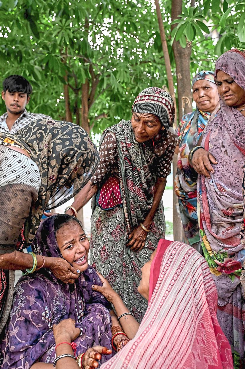 Women mourning their relatives while waiting outside the hospital mortuary in Ahmedabad. — AFP