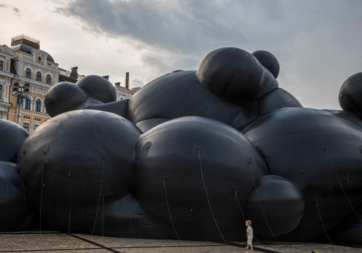In central Kyiv, a child inspects Oleksiy Sai’s 'Black Cloud', a chilling installation echoing Russia’s invasion with sounds of war. Photo: Reuters
