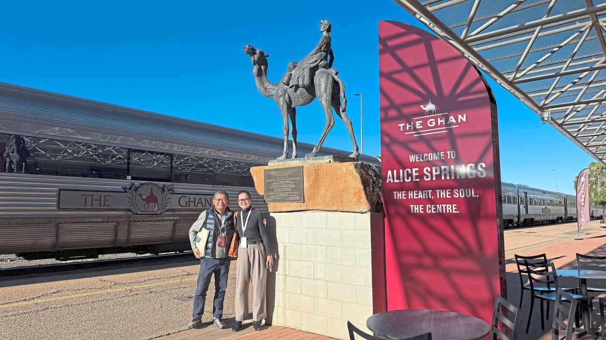 Kii and his daughter G standing next to a monument of an Afghan camel rider at Alice Springs.