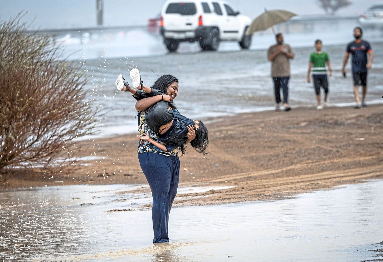 A woman and a child enjoying the wet weather in the emirate.
