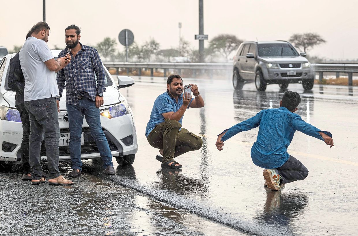 Grown men taking pictures of each other in the rain.