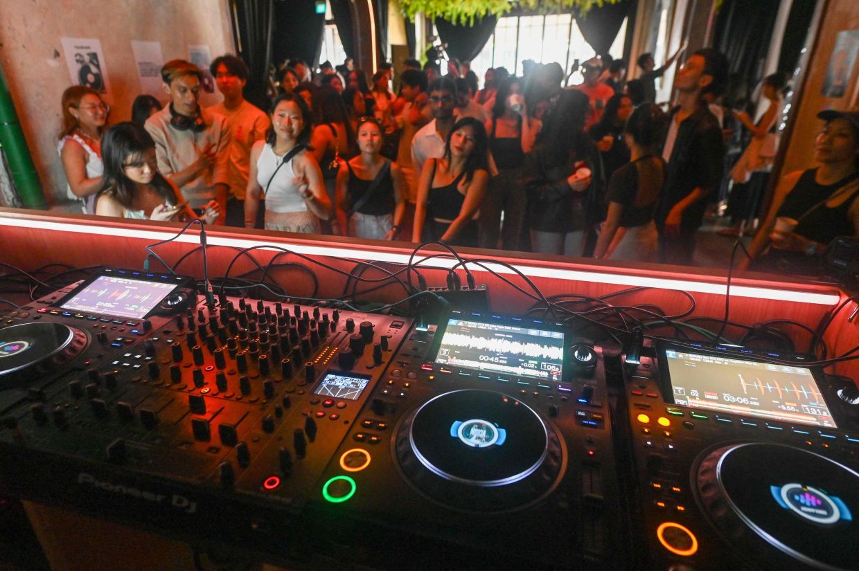 Attendees listening to music while drinking coffee at an alcohol-free clubbing event in Singapore.