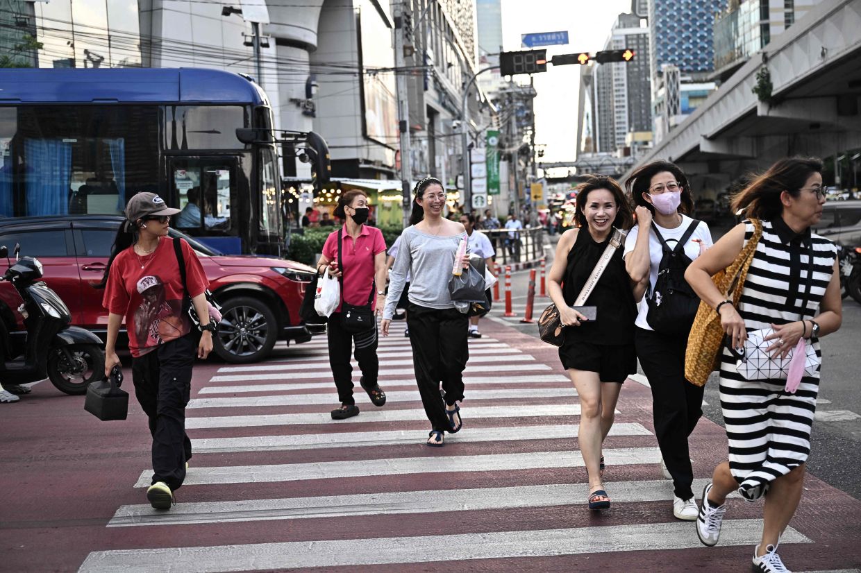 People run across a pedestrian crossing in Bangkok on Monday, June 16, 2025. -- Photo by Lillian SUWANRUMPHA / AFP