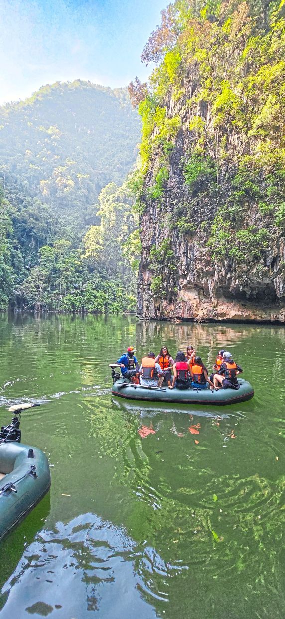 Gliding through a hidden valley, visitors float across Tasik Cermin’s emerald waters, where jungle-draped limestone cliffs rise like nature’s cathedral walls.