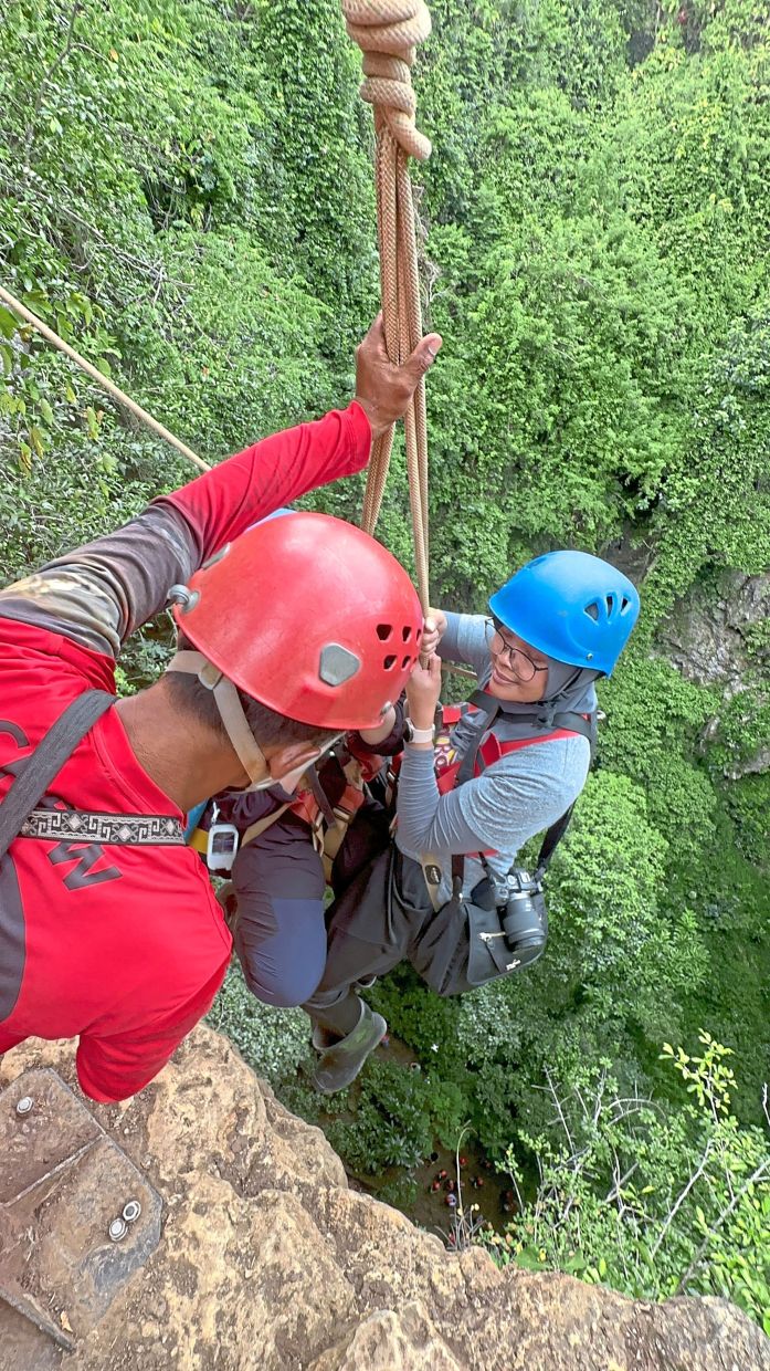 The lush greenery at the mouth of Jomblang Cave offers a surreal contrast to the shadows below, as explorers emerge from the cave’s underground tunnel system.