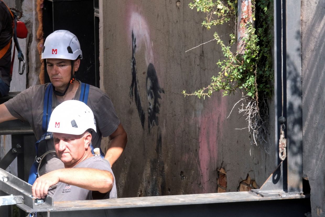 The Banksy mural appeared on San Pantalon palace in 2019 and it will be restored by Ifis art. Photo: Reuters 