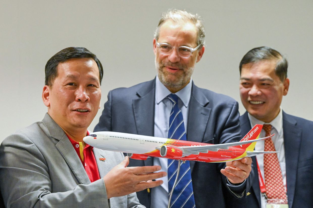 Airbus executive vice president of sales of commercial aircraft Benoit de Saint-Exupery (centre), presenting a model airliner as a gift to Vietjet CEO Dinh Viet Phuong (left) after a signing ceremony at the Singapore Airshow in Singapore on Feb 22, 2024. Vietnamese carrier Vietjet has ordered 100 single-aisle A321neo jets from Airbus, the European plane maker said on June 17, 2025, in the latest deal announced at the Paris Air Show.- AFP