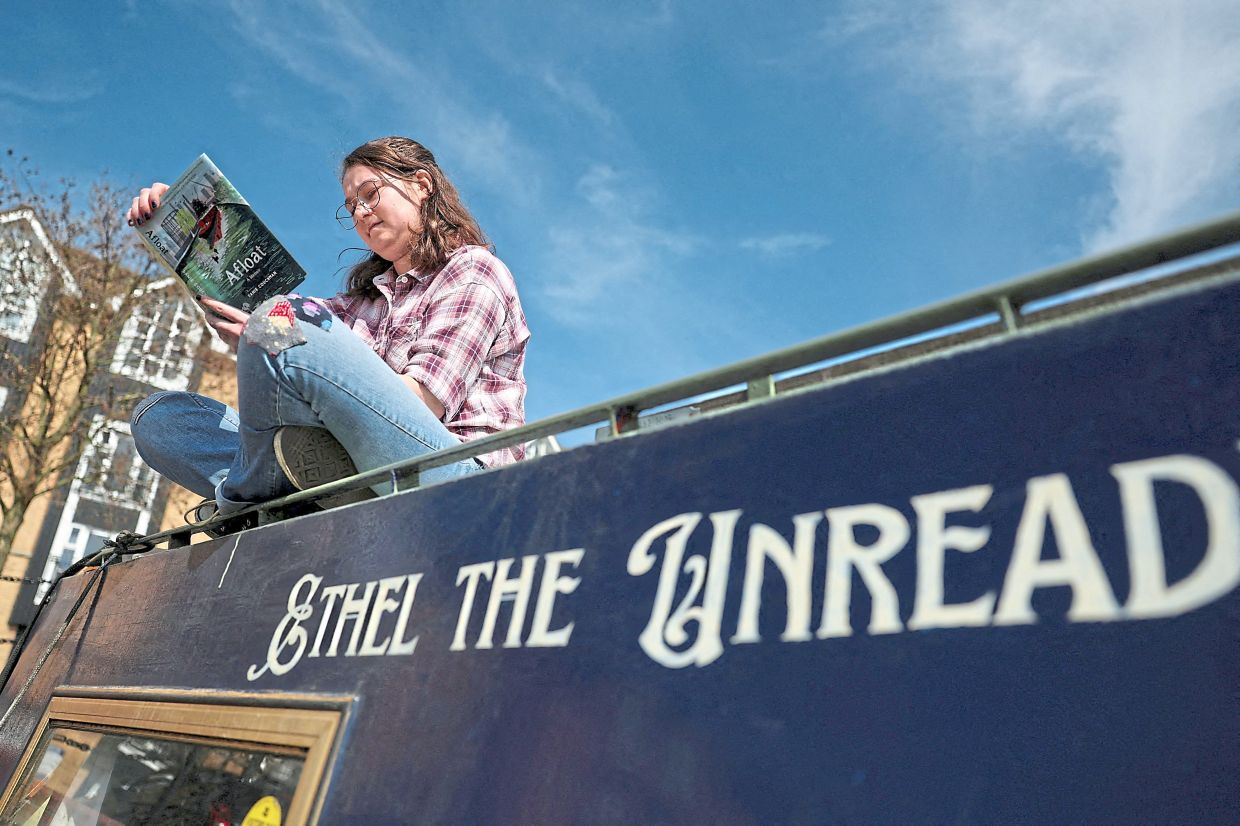 Chonofsky reading a book on her houseboat, which she named with the combination of her grandmother’s narrowboat name and the name of an Anglo-Saxon English king, in Apsley, Hertfordshire.