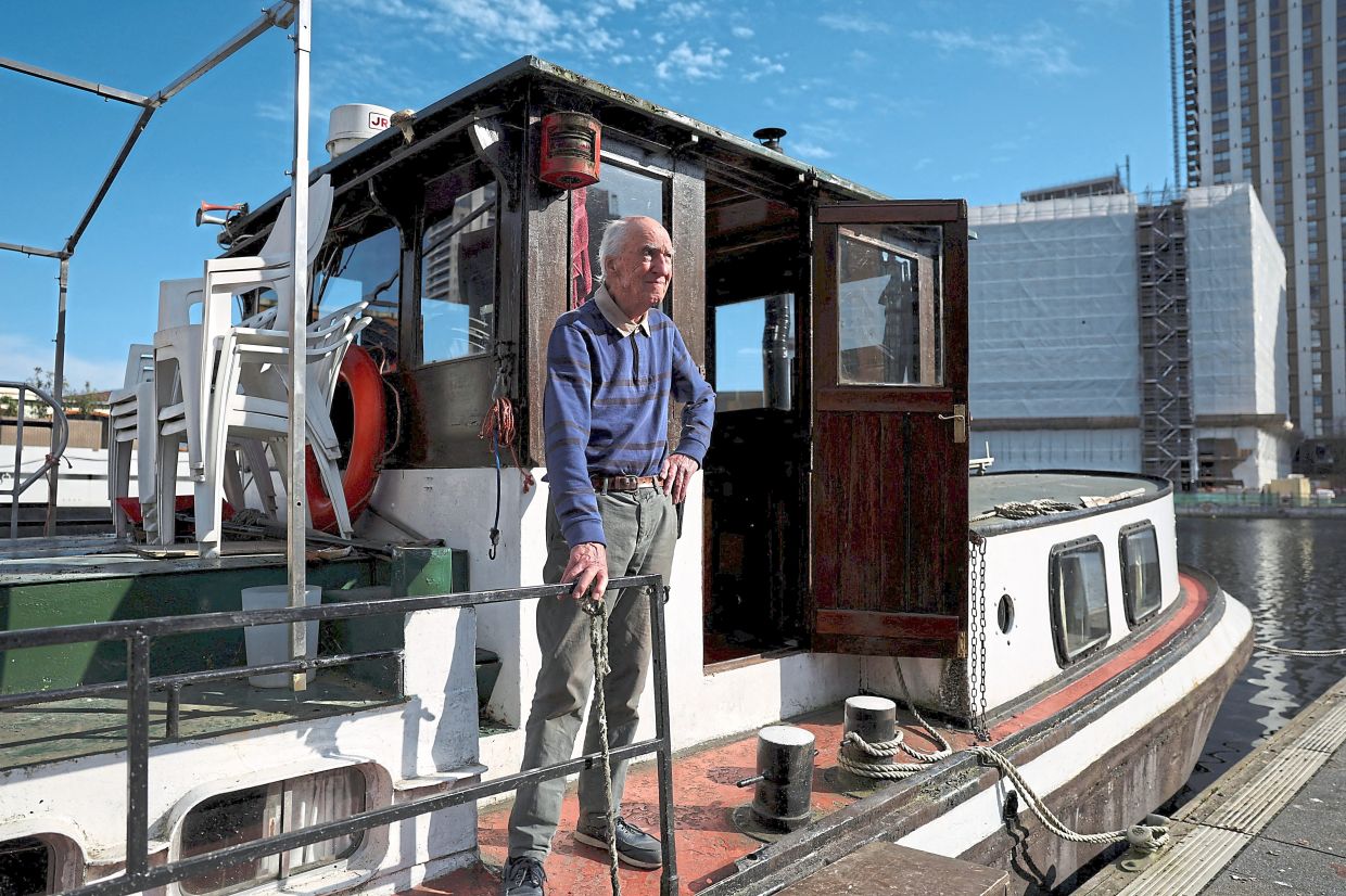 John Robin Purdue, a former hotel barge operator, enjoying some sun at his houseboat at Canary Wharf in London. — Reuters