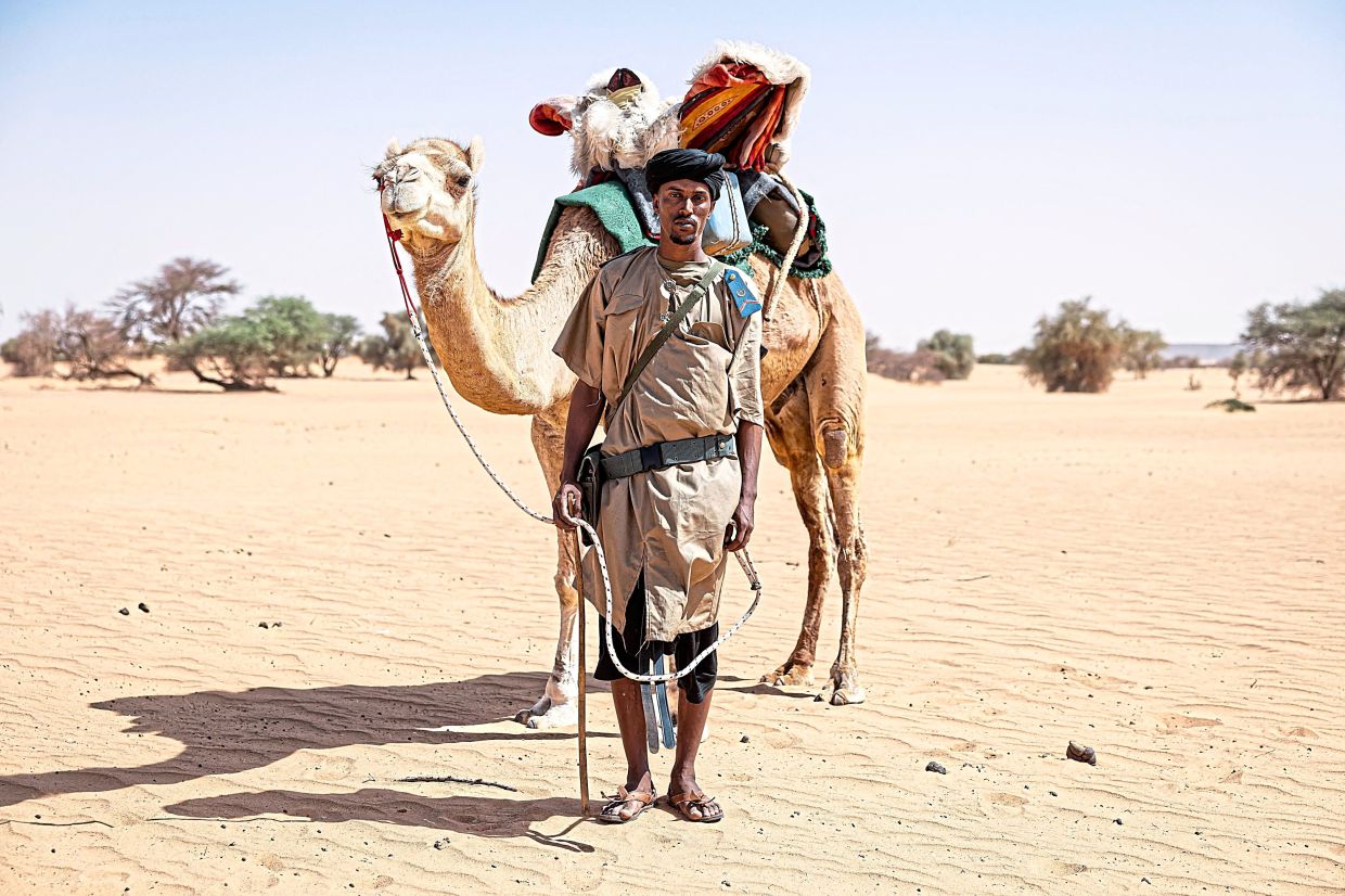 Sidnq, a member of the Mehariste National Guard, posing for a portrait next to his camel, near the Malian border. — AFP