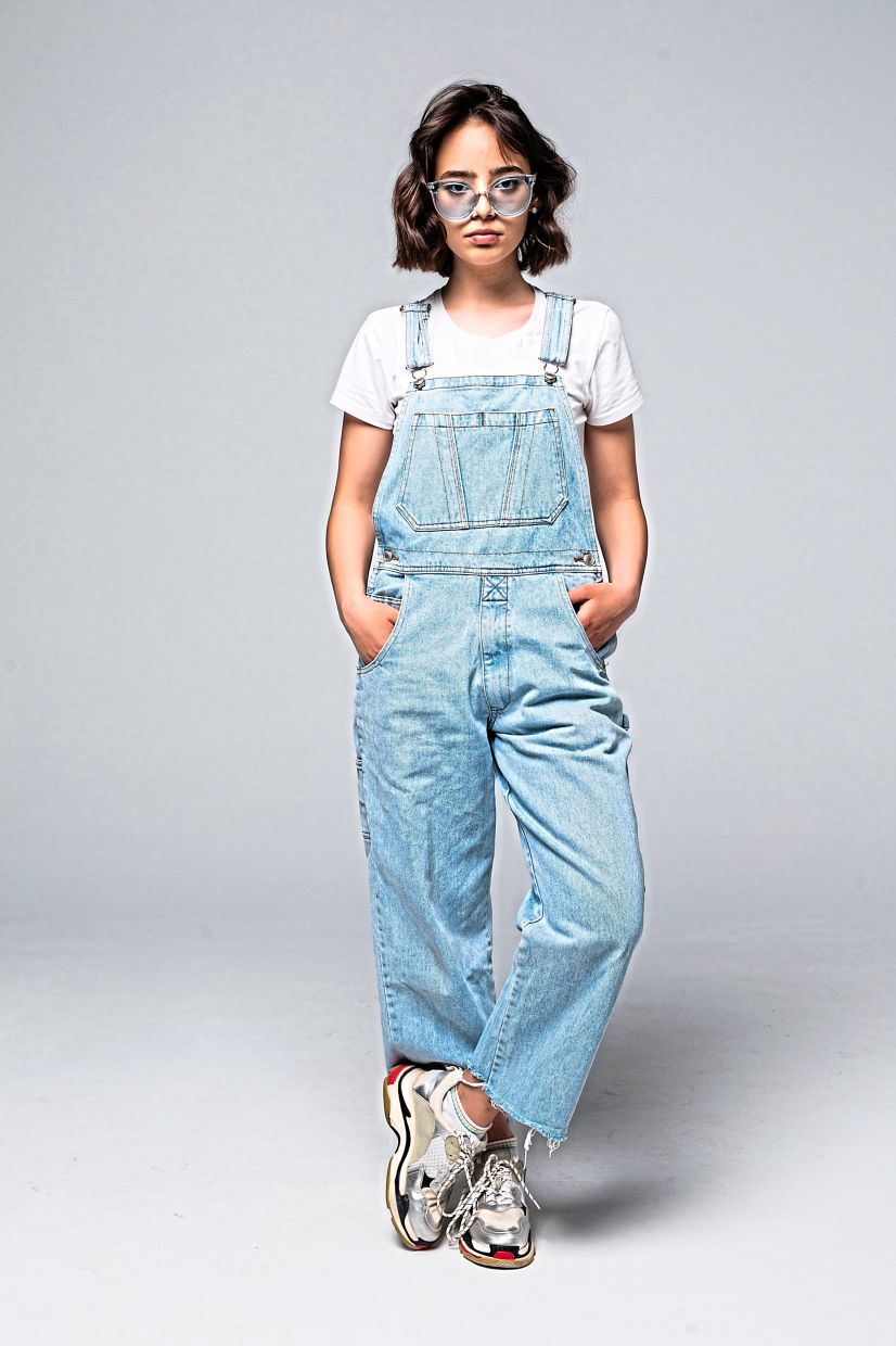 Dungarees plus sneakers and a white T-shirt make for a hip look. As there's plenty of fabric in a loose pair, some are opting for shorter tops. Photo: Freepik