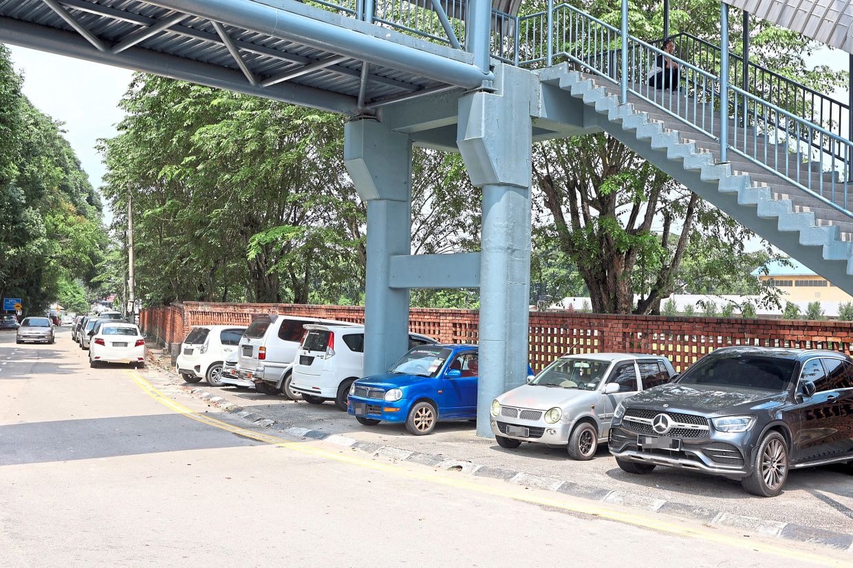 Vehicles parked under a pedestrian bridge in Skudai.