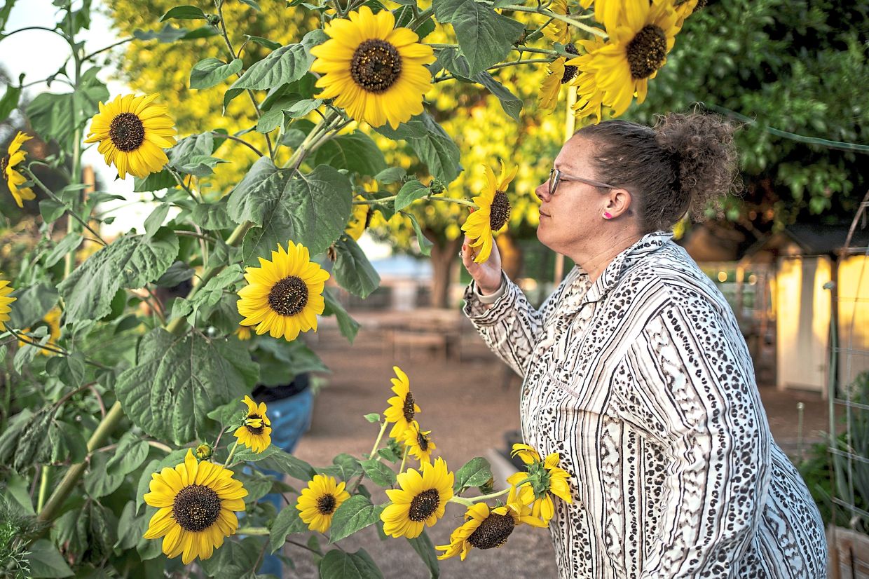 Sabrina Mathisen stops to smell the flowers at a garden.