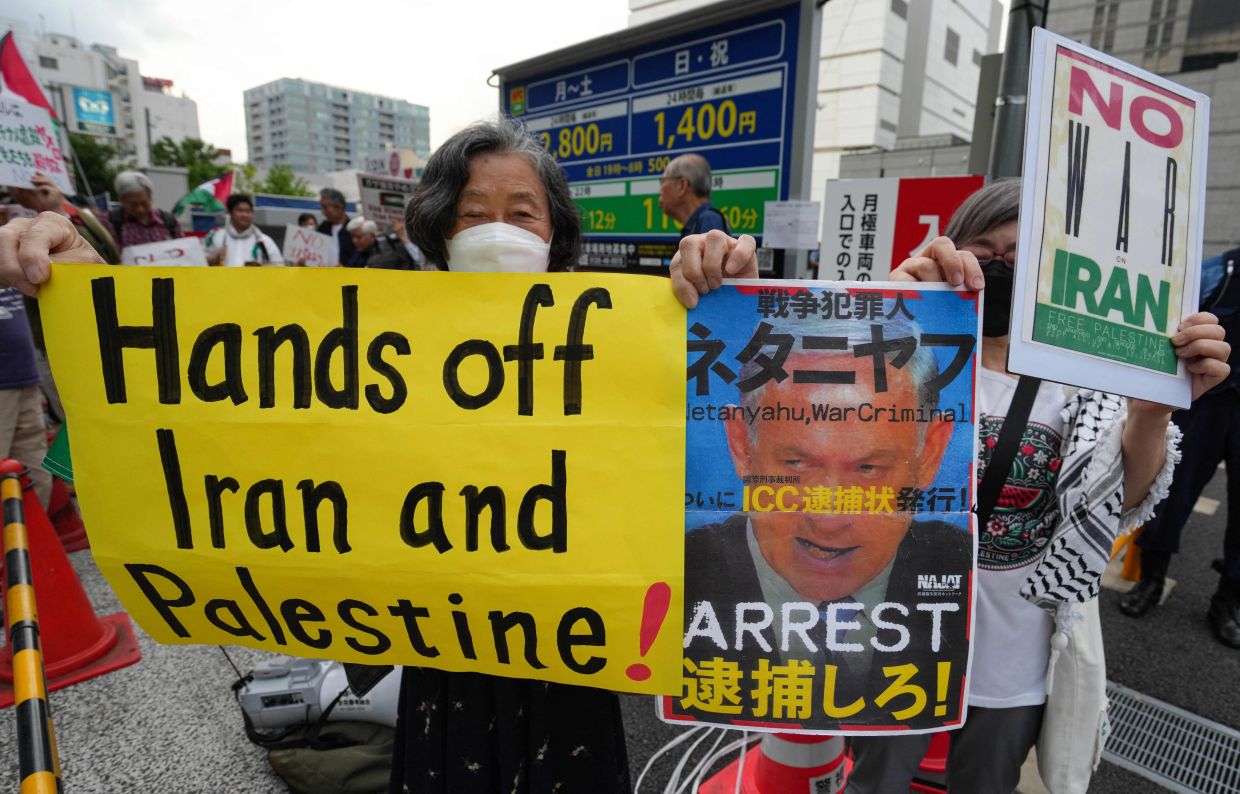Anti-Israel protesters holding placards as they demonstrate against the ongoing conflict between Israel and Iran near the Israeli Embassy in Tokyo on June 20, 2025. - AFP