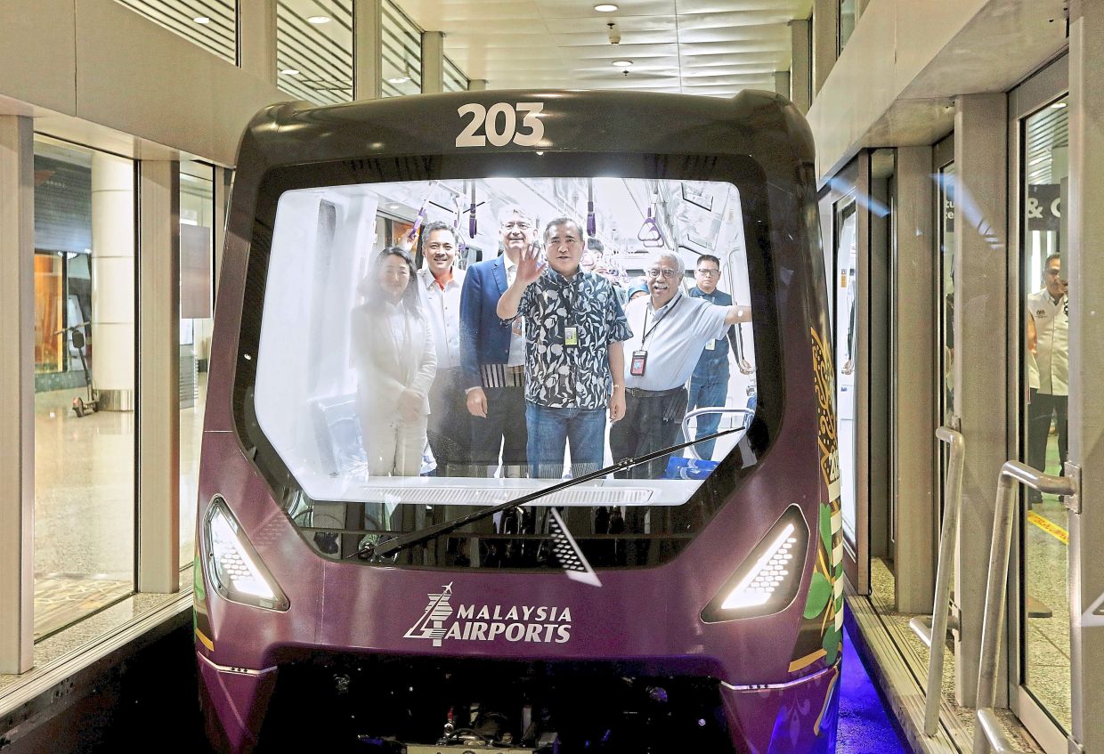 Testing it out: Loke and Izani (second from left) using the aerotrain at KLIA. — YAP CHEE HONG/The Star