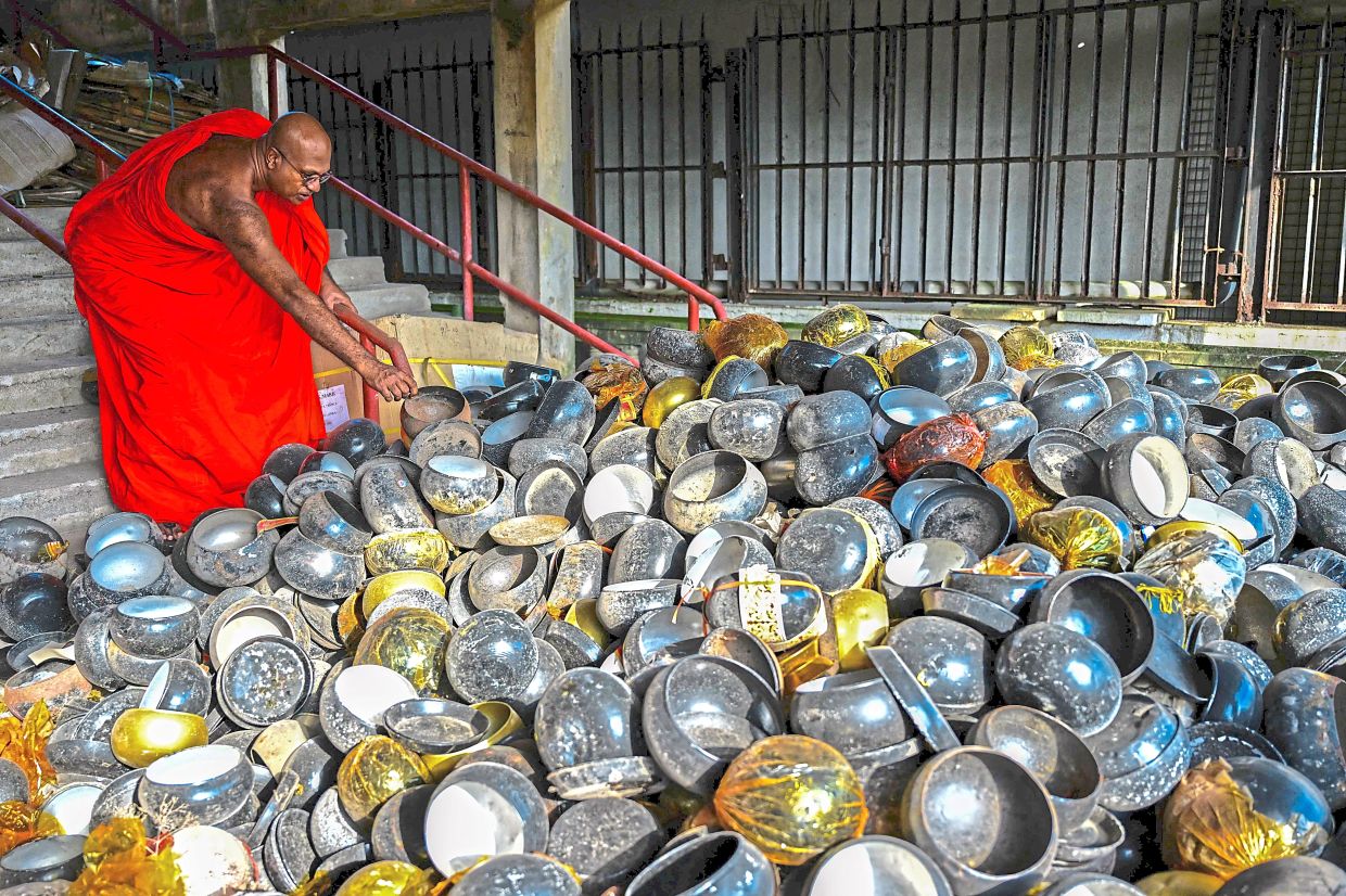 Unfit, unused and unsightly: Assagi showing the poor-quality begging bowls donated at the Gangaramaya temple in Colombo. — AFP 